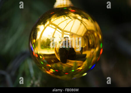 A reflected view of a man in his thirties taking a photograph (self portrait) in a Christmas tree bauble Stock Photo