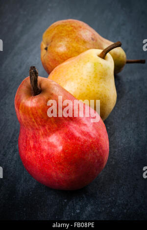 Three bright ripe bartlett pears on dark grey background Stock Photo