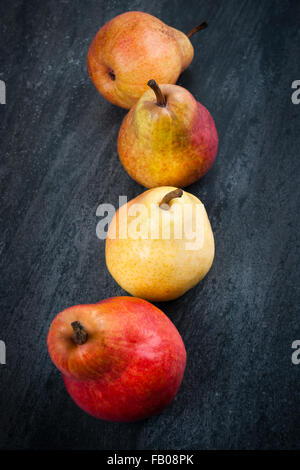 Four bright ripe bartlett pears on dark grey background from above Stock Photo