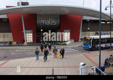 'The Malls' in Basingstoke as viewed from outside the train station and pedestrians crossing a zebra crossing in front of a bus. England, UK Stock Photo