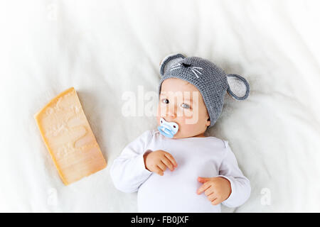 Baby boy in mouse hat lying on blanket with cheese Stock Photo