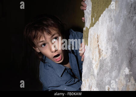 Lonely little boy in a dark cellar Stock Photo