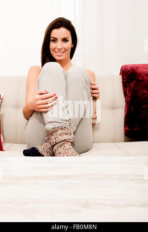 Young beautiful woman sitting on the couch wearing worn-out socks Stock Photo