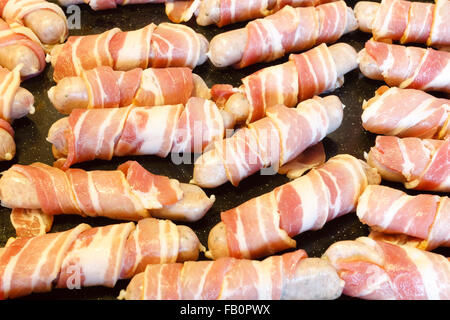 Traditional Christmas food of sausages wrapped in streaky bacon, on a baking tray. England, UK