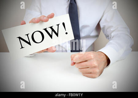 Man holding up a card that says now. Stock Photo