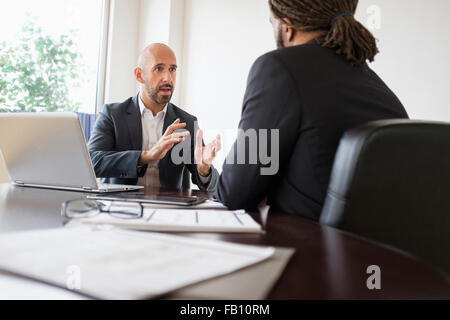 Two businessmen having discussion at desk in office Stock Photo