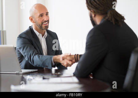 Smiling businessmen shaking hands in office Stock Photo