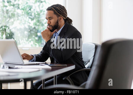 Concentrated businessman working with laptop at desk in office Stock Photo
