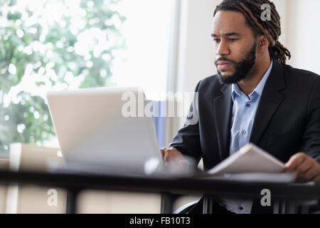 Concentrated businessman working with laptop at desk in office Stock Photo