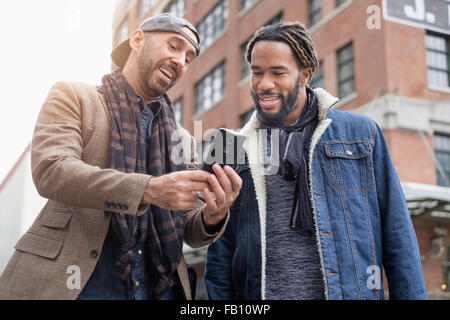 Smiley homosexual couple taking selfie with smart phone in street Stock Photo