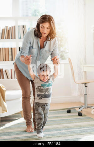 Mother holding son (2-3) making first steps Stock Photo