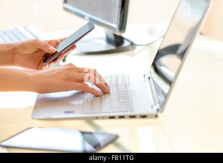 Business woman texting and typing on laptop keyboard Stock Photo