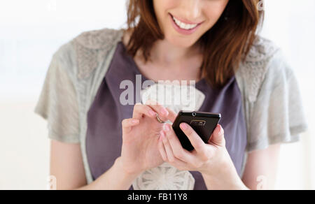 Smiling woman text messaging using smartphone Stock Photo