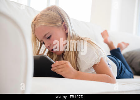 Girl (6-7) using digital tablet on sofa Stock Photo