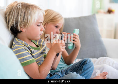 Boy (4-5) and girl (6-7) playing games on smart phones Stock Photo