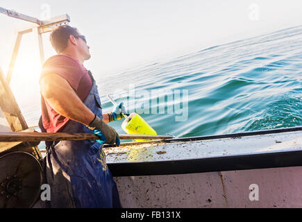 Fisherman throwing lobster buoy Stock Photo