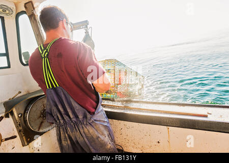 Fisherman throwing lobster trap Stock Photo