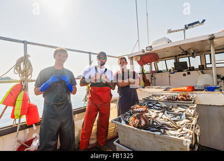 Portrait of three fishermen standing on boat Stock Photo