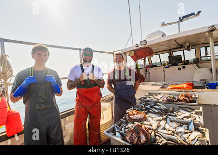 Portrait of three fishermen standing on boat Stock Photo