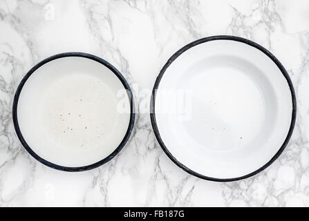 Empty white vintage enamel plates on white marble background Stock Photo