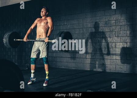 Man weight training lifting barbell in gym Stock Photo
