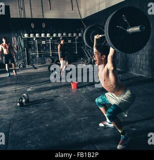 Man shouting whilst lifting barbell in gym Stock Photo