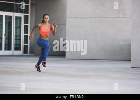 Front view of young woman wearing sports clothing in running stance Stock Photo