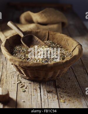 Organic mix of pumpkin, poppy, sunflower and flax seeds in wicker bowl Stock Photo