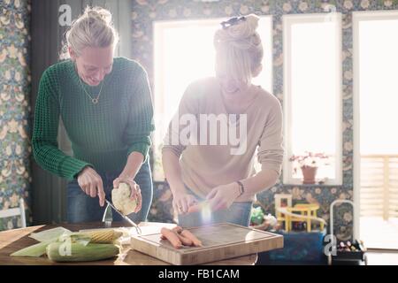 Two female friends preparing organic vegetables in kitchen Stock Photo