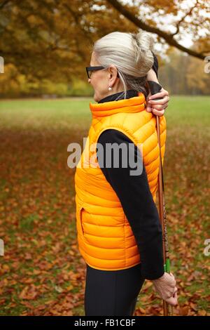 Senior female nordic walker exercising with walking poles in park Stock Photo