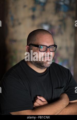 Bearded mid adult man wearing eye glasses, arms folded, looking at camera smiling Stock Photo