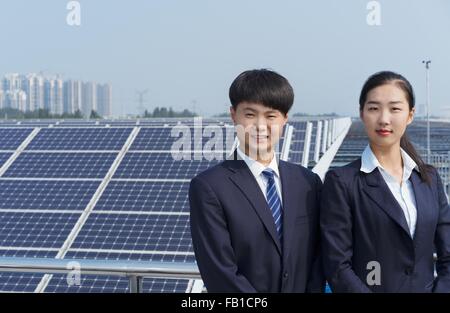 Businessman and businesswoman on roof of solar panel assembly factory, Solar Valley, Dezhou, China Stock Photo