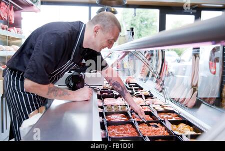 Butcher serving fresh food from refrigerator in butchers shop Stock Photo