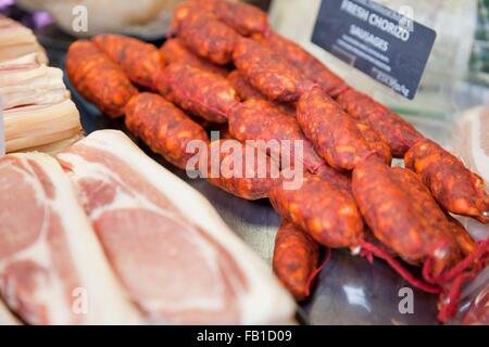 Bacon rashers and chorizo sausages in refrigerator at butchers shop Stock Photo
