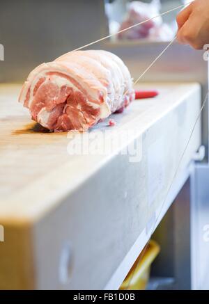 Close up of butchers hands tying meat joint in butchers shop Stock Photo