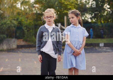 Portrait of two elementary schoolgirls standing in school playground Stock Photo