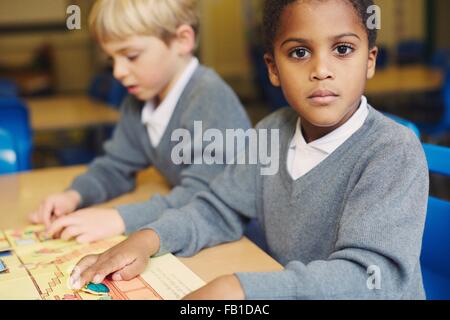 Portrait of boy doing puzzle at desk in elementary school classroom Stock Photo