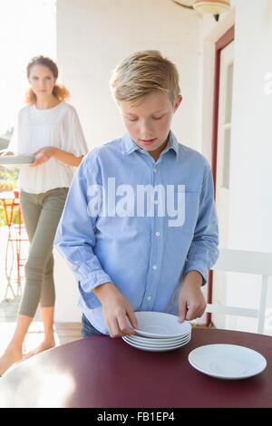 Boy preparing plates on patio table