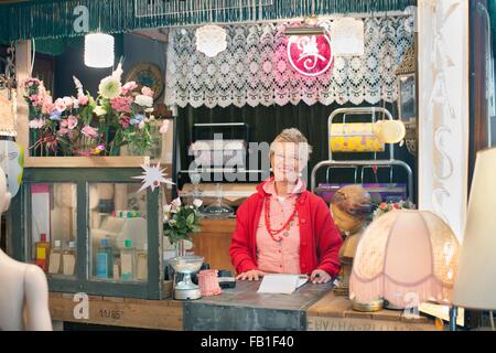 Portrait of mature woman behind vintage shop counter Stock Photo