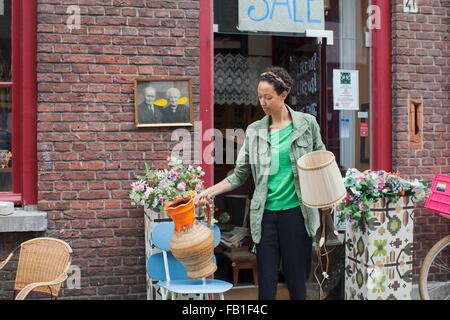 Female customer with jug and lamp outside vintage shop Stock Photo