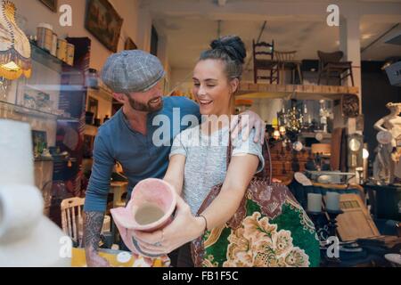 Young woman holding pink vase in vintage shop Stock Photo