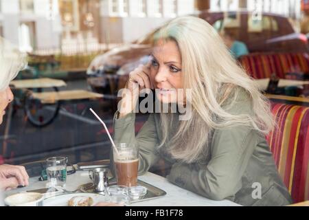 Mother and daughter sitting together in cafe, seen through cafe window Stock Photo