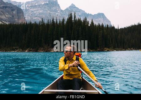 Front view of mid adult man paddling canoe, looking away, Moraine lake, Banff National Park, Alberta Canada Stock Photo