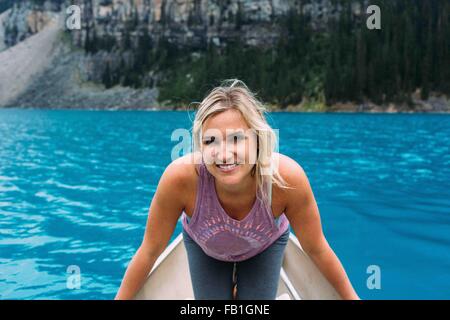 Portrait of mid adult woman in canoe on Moraine lake, looking at camera smiling, Banff National Park, Alberta Canada Stock Photo