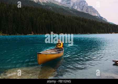 Mid adult man paddling canoe on Moraine lake, looking at camera, Banff National Park, Alberta Canada Stock Photo