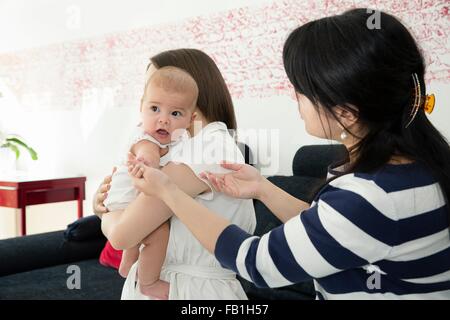 Young woman and baby daughter with grandmother on sofa Stock Photo