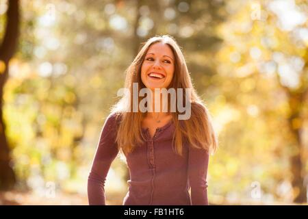 Sunlit portrait of long haired young man in autumn forest Stock Photo