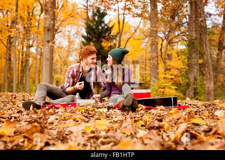 Happy young couple having picnic in autumn forest Stock Photo