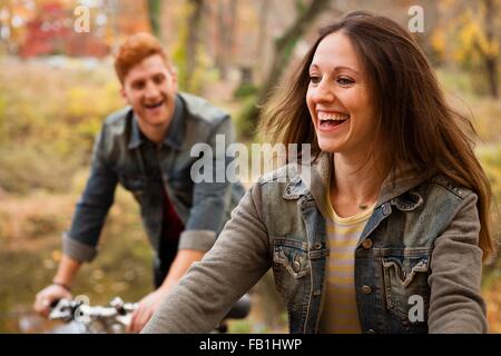 Young couple cycling along riverside in autumn