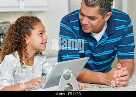 Father and daughter using digital tablet face to face smiling Stock Photo